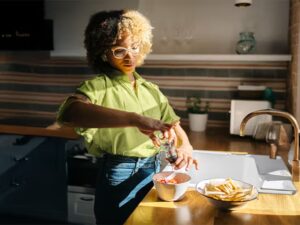 A person prepares a bowl of food, grinding pepper over it next to a bowl of tortilla chips